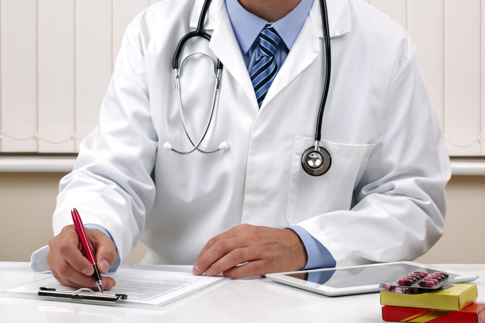 Doctor writing patient notes on a medical examination form or prescription