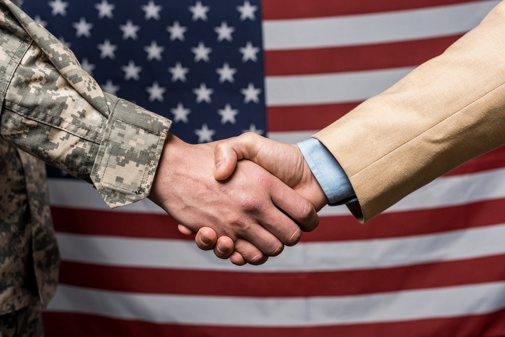 military men shaking hands near american flag